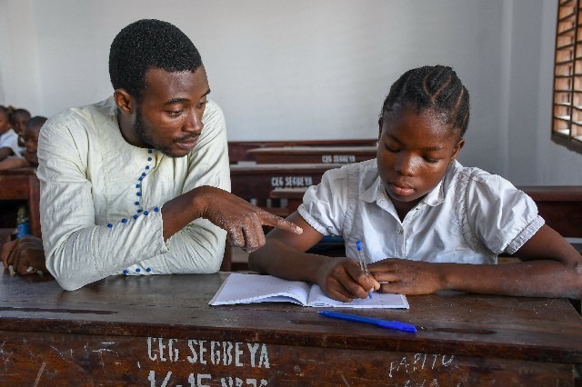 Jeune écolière écrivant dans un cahier et son professeur